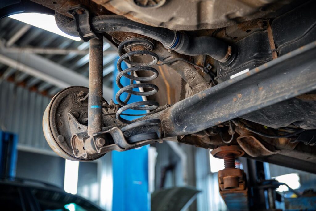 Close-up of a car's rear suspension system for repair, showcasing a coil spring, shock absorber, and axle components in a Las Vegas workshop.